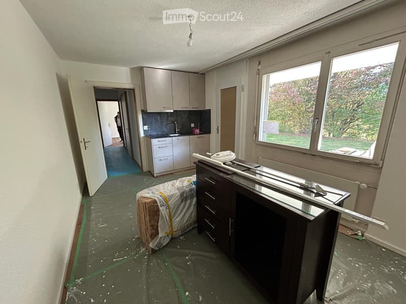 Kitchen with white cabinets, a sink, and a countertop, partially under renovation with exposed tools and materials.
