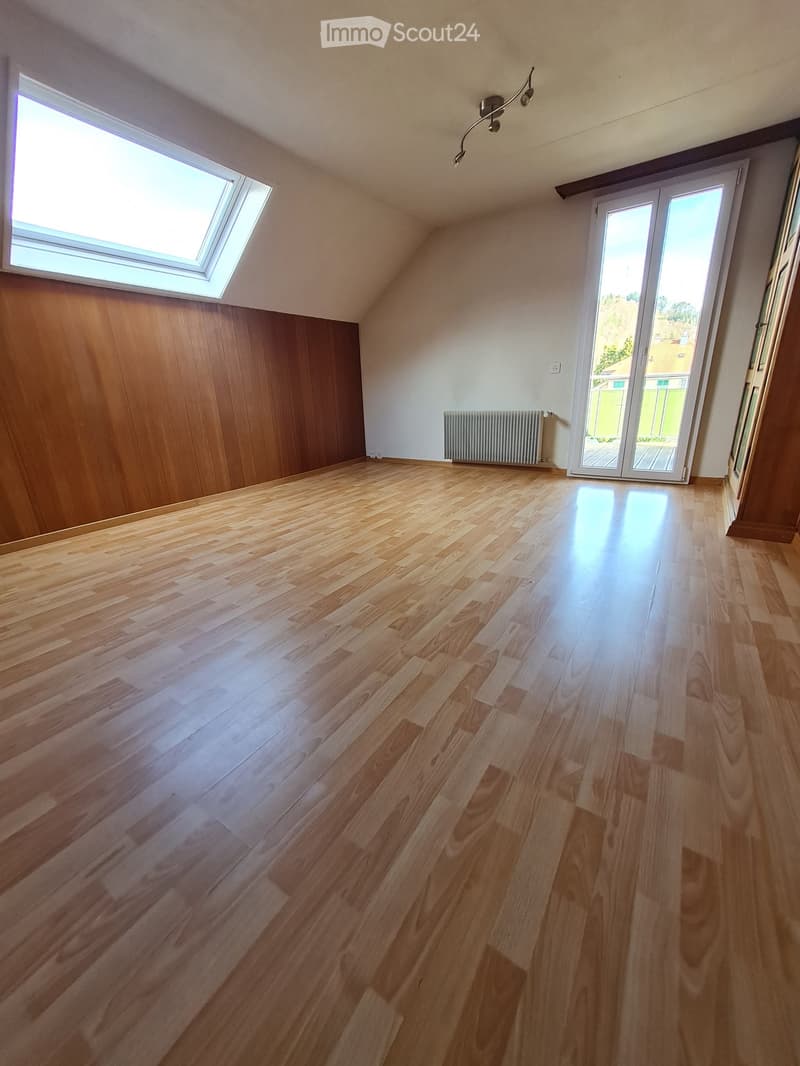 Empty room with wooden flooring, white walls, large window, sliding glass door leading outside, and a radiator.