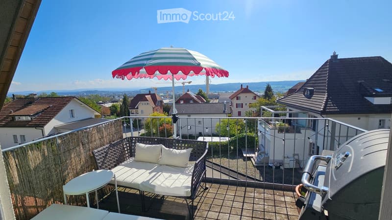 Balcony with a view of the city, featuring a white sofa, small table, and umbrella.