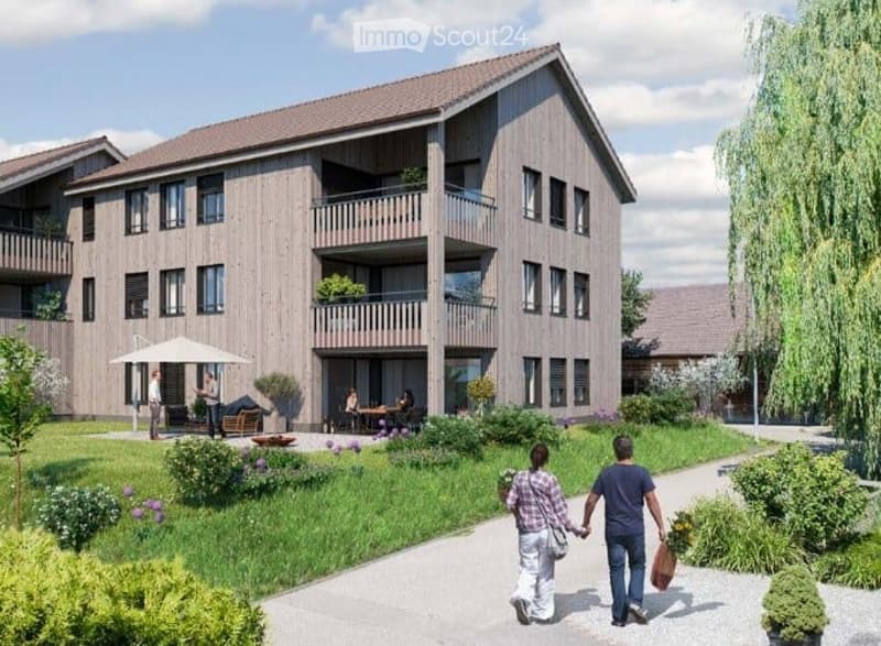 Modern apartment building with balconies and a community garden, surrounded by greenery