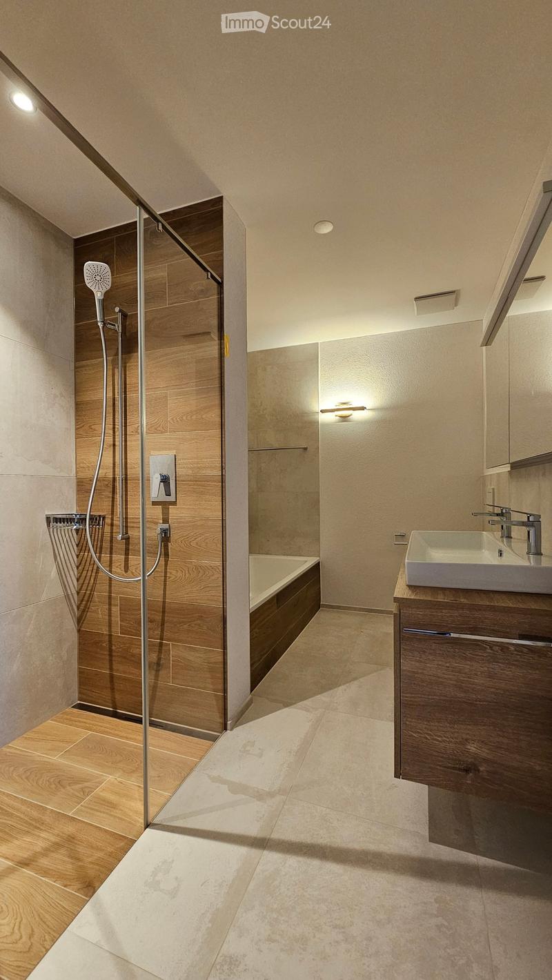 modern bathroom with wooden walls and floor, white bathtub, white sink, silver faucet, wooden cabinet