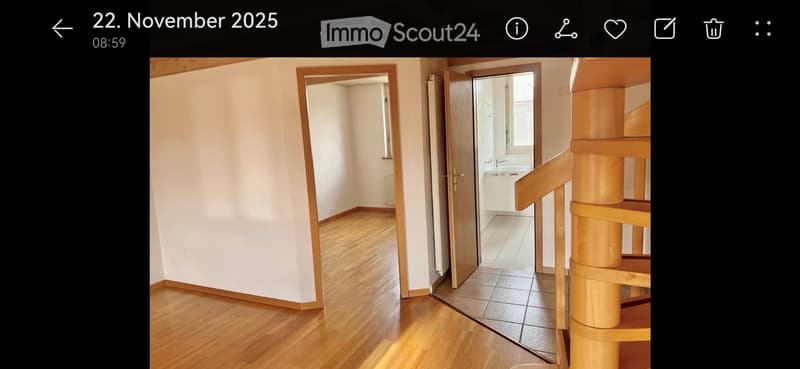 Empty room with wooden flooring and white walls, featuring an open doorway leading to a tiled bathroom area.