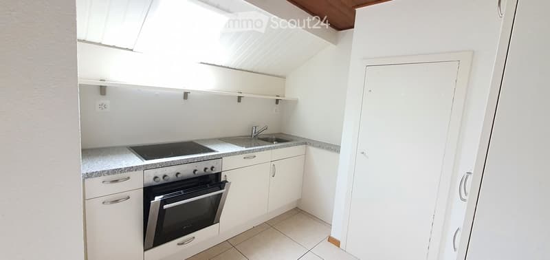 Compact kitchen with white cabinets, a built-in oven, a sink with a faucet, and a small countertop.