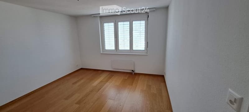 Empty room with wooden flooring, white walls, and a window with blinds. No furniture or equipment present.