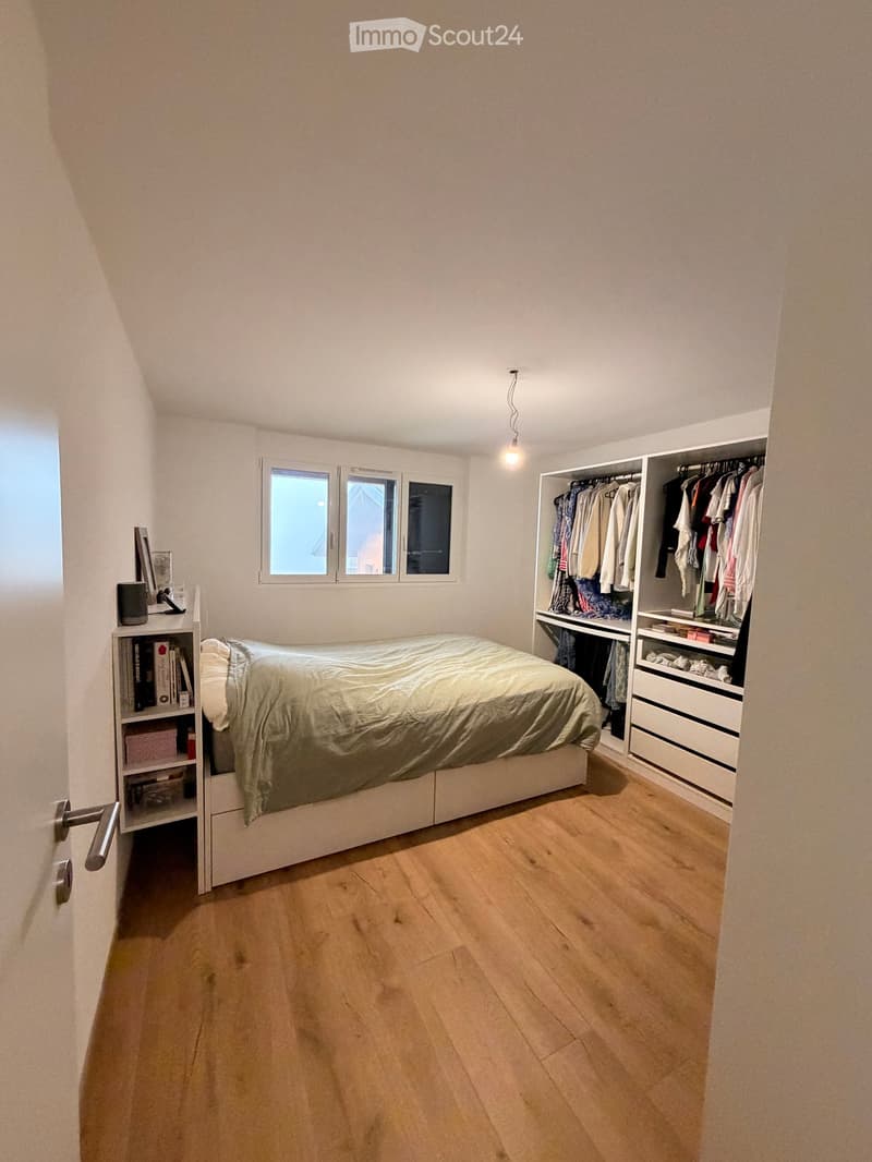 Bedroom with a single bed, built-in wardrobe, bookshelf, and a window with three panes.