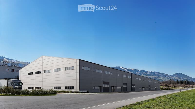 industrial building, concrete walls, multiple garages, large windows, mountains in the background