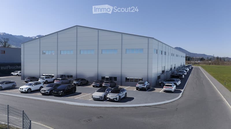 large industrial building, multiple cars parked in front