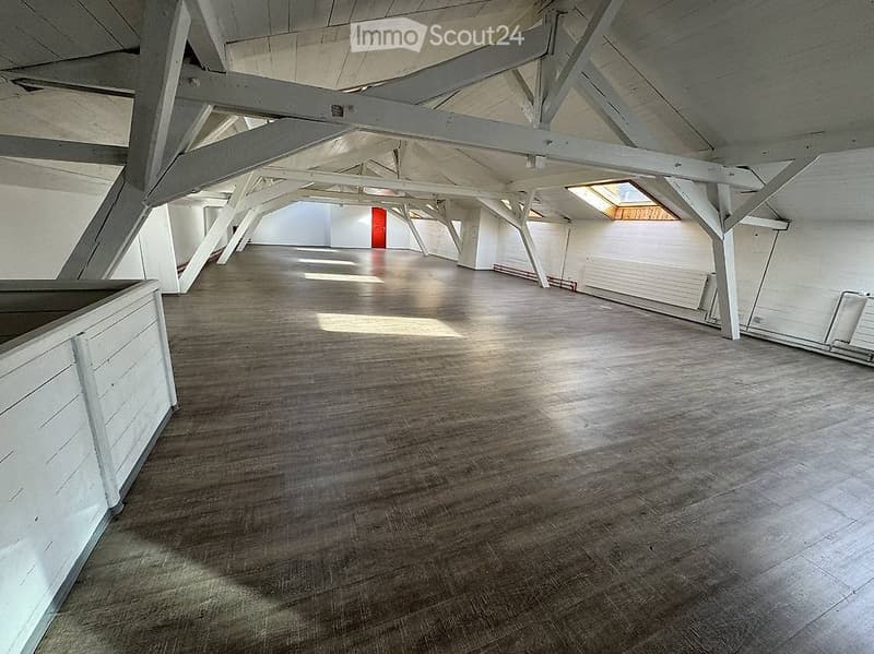 Empty room with wooden floor and white wooden beams on the ceiling. No furniture or equipment.