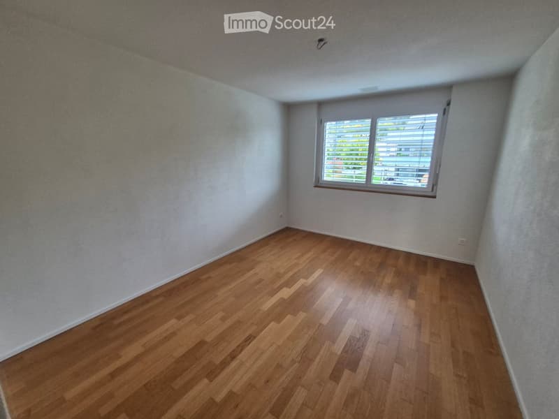 Empty room with wooden flooring and white walls, featuring a single window with blinds.