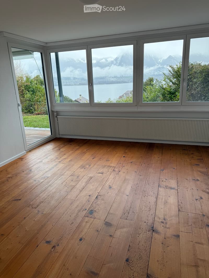 empty room, hardwood floors, large windows, white walls, sliding door leading to wooden deck, views of mountains and water