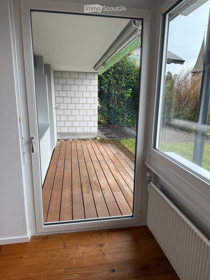 open sliding door, wooden balcony, white radiator, wooden floor, white walls