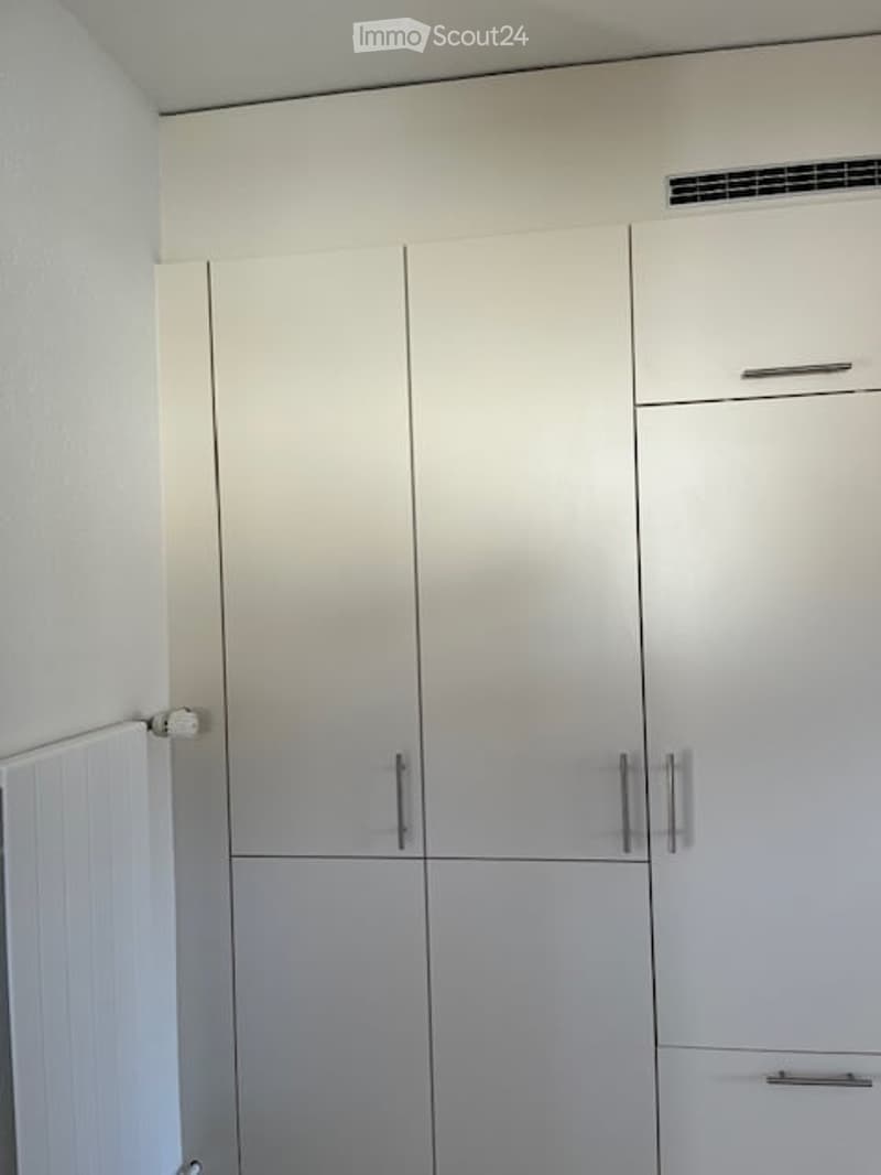 Built-in wardrobes, mounted air conditioning unit, white walls, drawers, sliding doors.