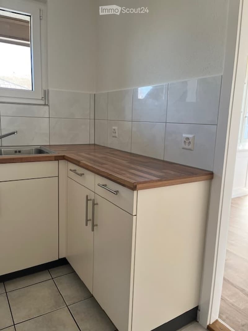 white cabinets, wooden countertops, tiled floor, small stainless steel sink