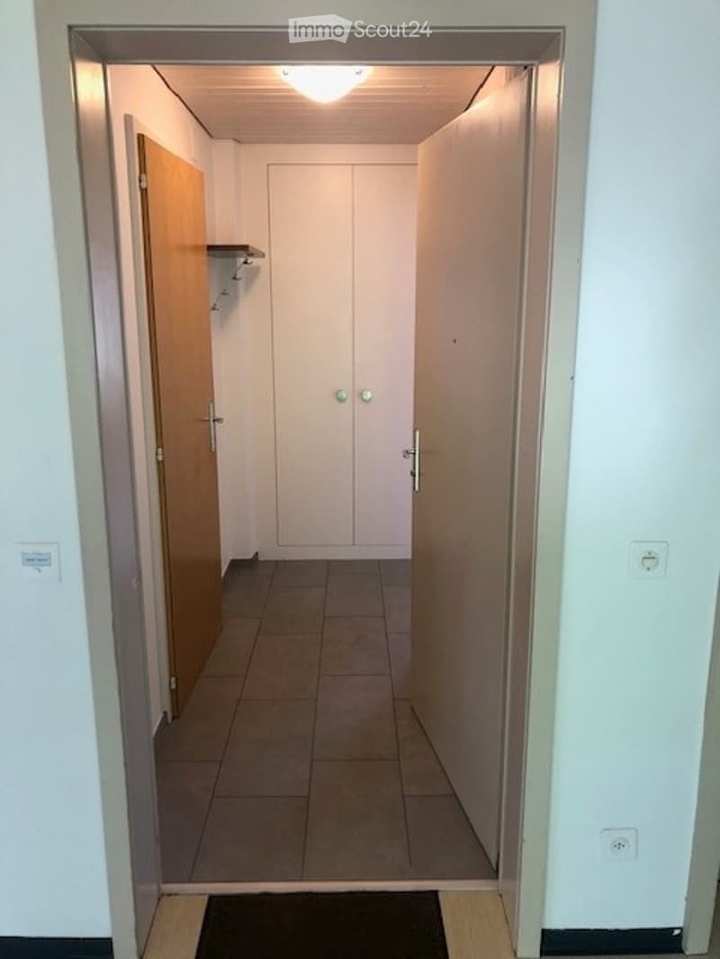 Empty hallway with tiled floor, white walls, and two closed doors on either side.