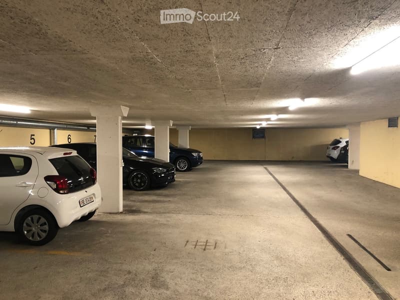 Underground parking area with several parked cars, concrete floors, and numbered sections.