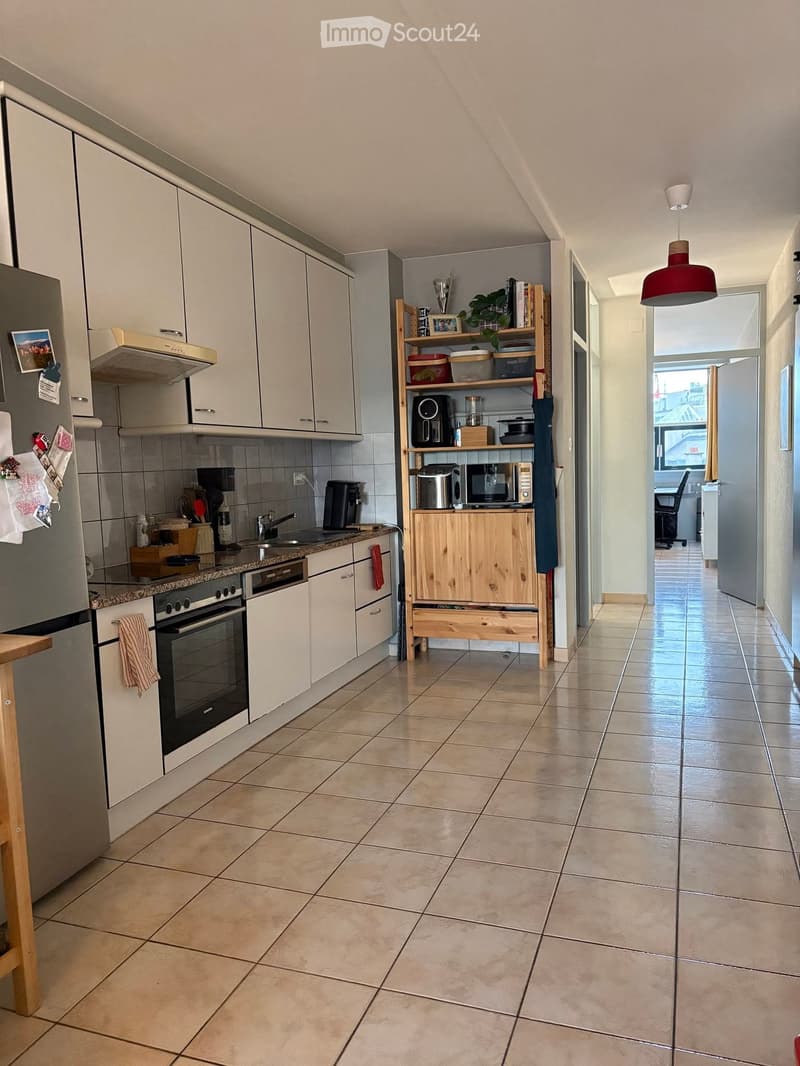 Modern kitchen with white cabinets, stainless steel appliances, tiled floor, and a wooden shelf unit holding various kitchen items.