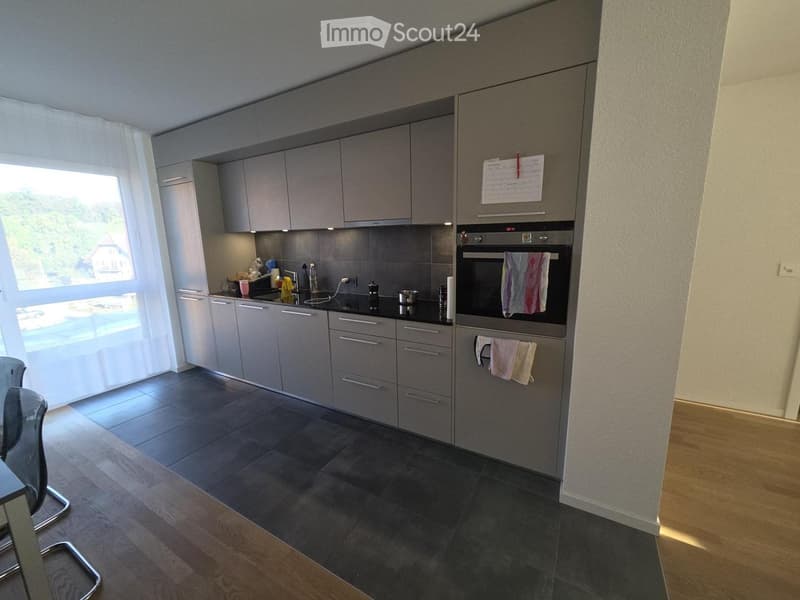 Modern kitchen with grey cabinets, stainless steel oven, and dark countertops.
