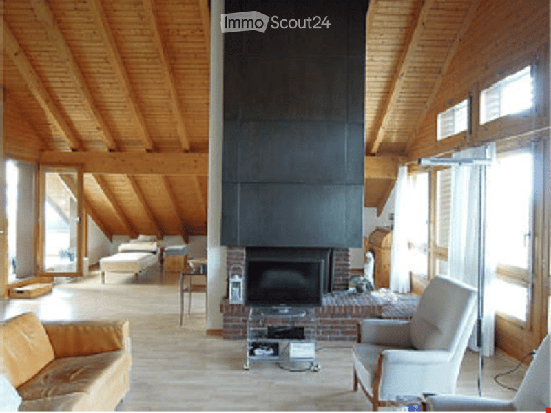 Bright living room with wooden beams, large windows, fireplace, sofa, armchair, coffee table, side table.