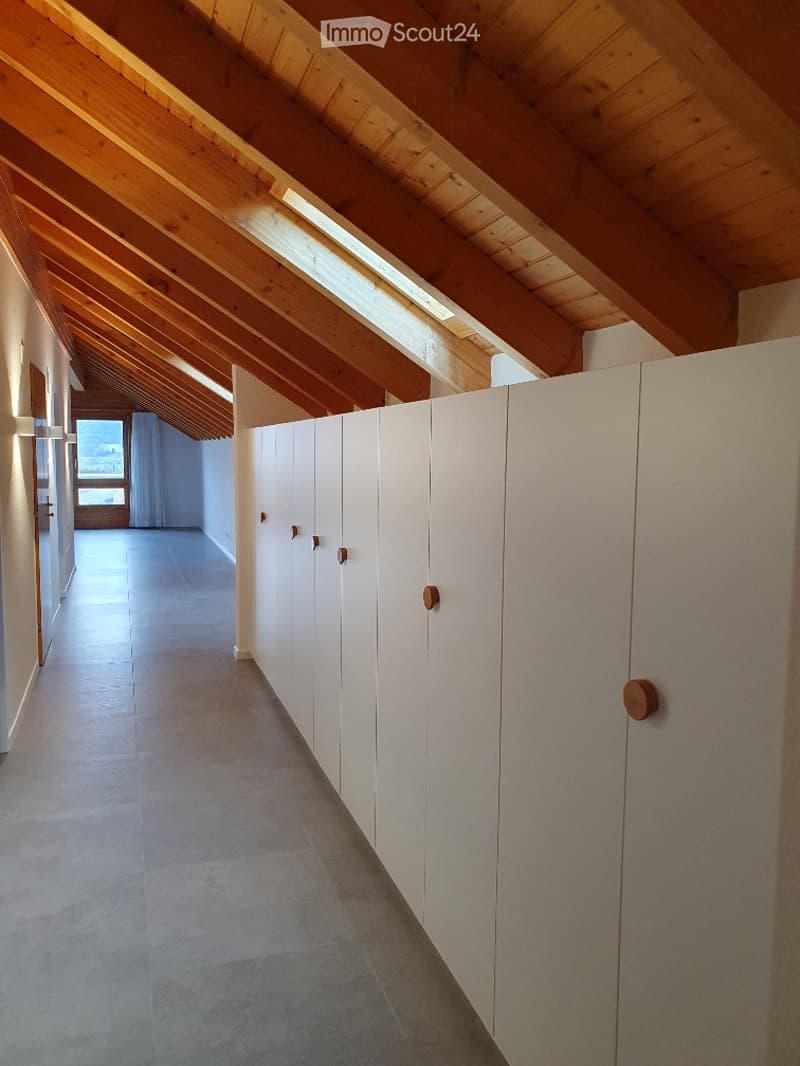 Bright hallway with white built-in cabinets, wooden ceiling beams, and large windows at the end.