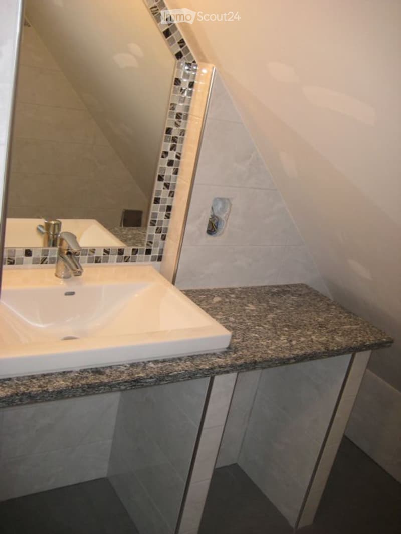 bathroom with white sink, mirror with tiled backsplash, gray granite countertop, slanted ceiling