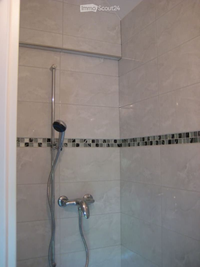 tiled walls, shower area, silver shower head and faucet