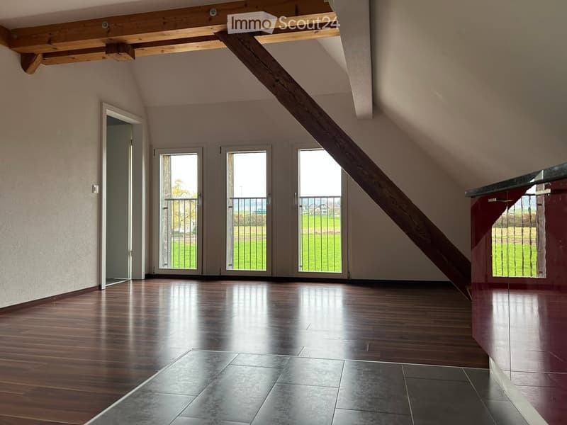 empty room with wooden floor, large windows, balcony, white walls, wooden beam