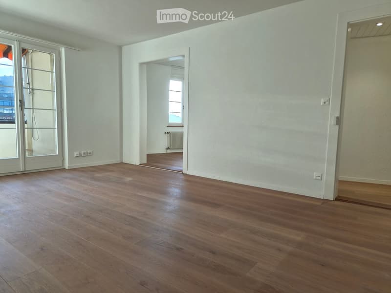 Empty room with wooden flooring, white walls, and large windows. No furniture or equipment present.