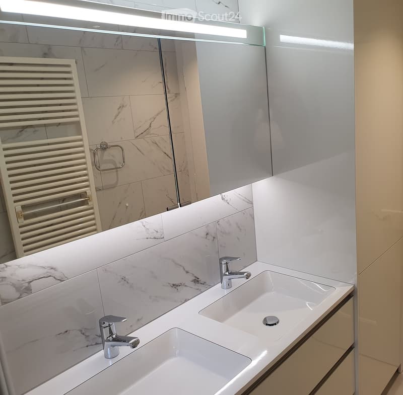 Modern bathroom with a double sink, chrome faucets, a large mirror, and a white radiator.