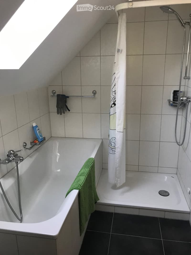 white bathtub, white tiles, green towel, shower with shower curtain, ceiling light