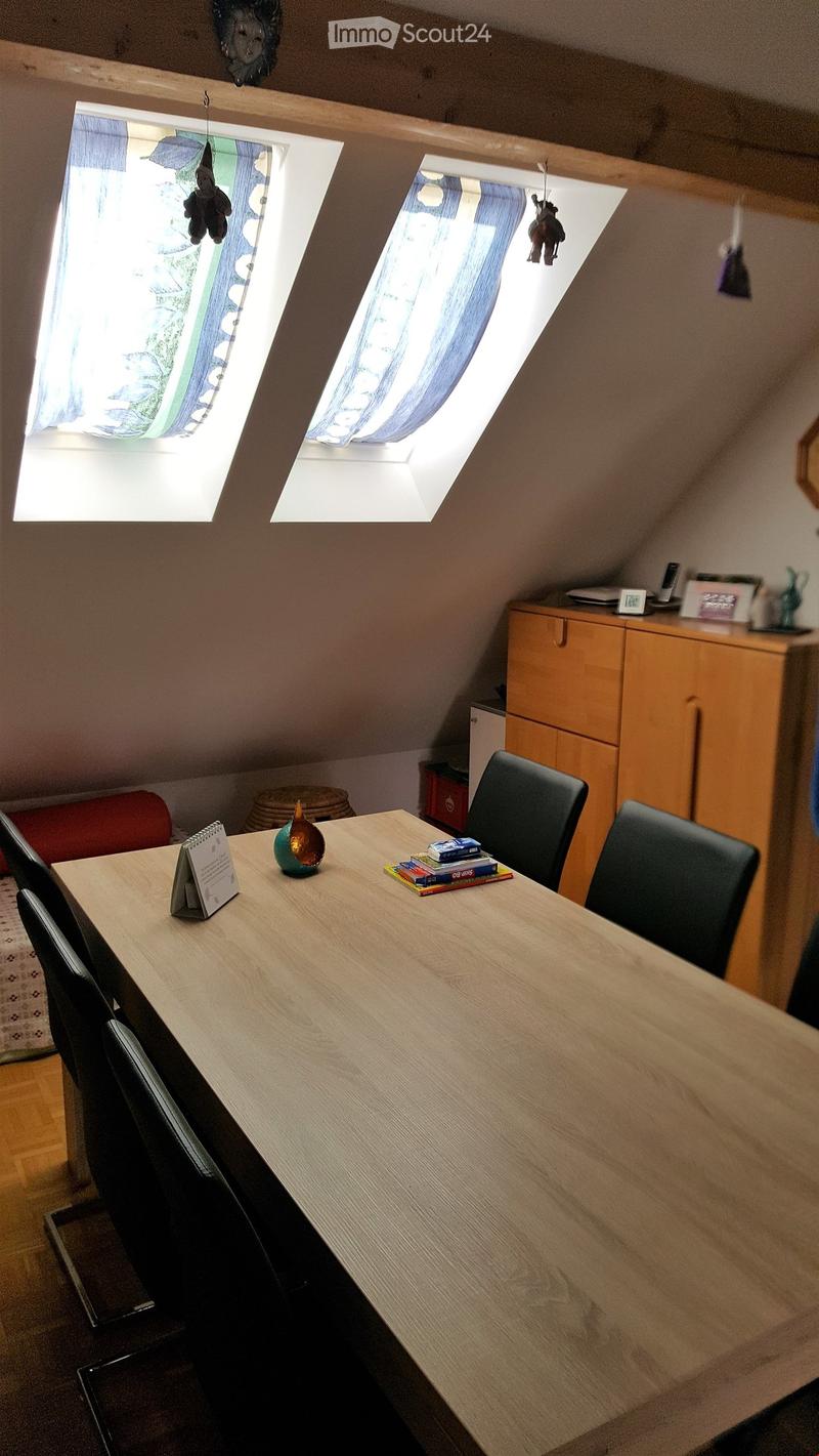 Wooden table, four black chairs, wooden cabinet, desk lamp, two windows with blue covers