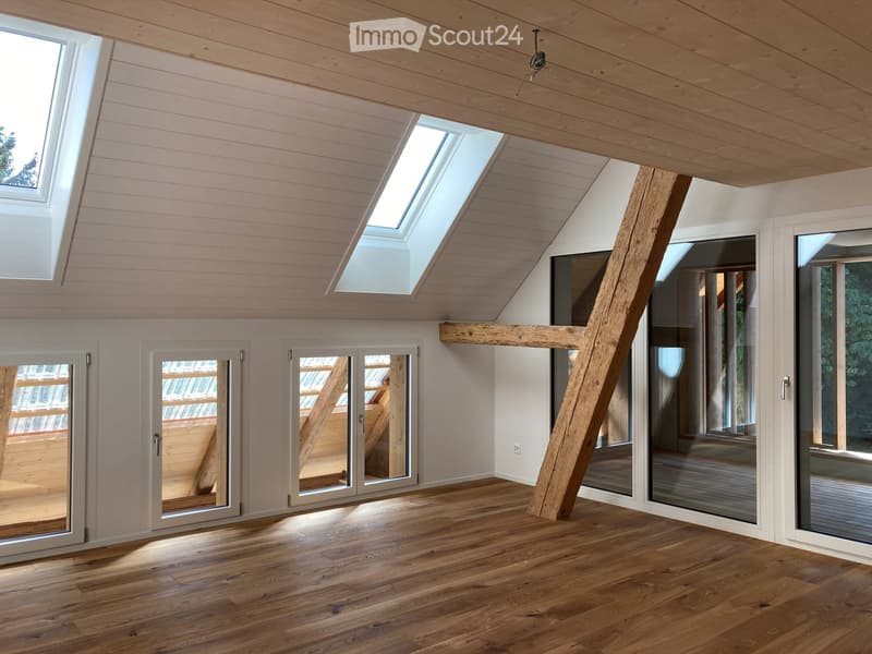 Bright, airy room with wooden floors, white walls, skylights, and large glass doors leading to a deck.