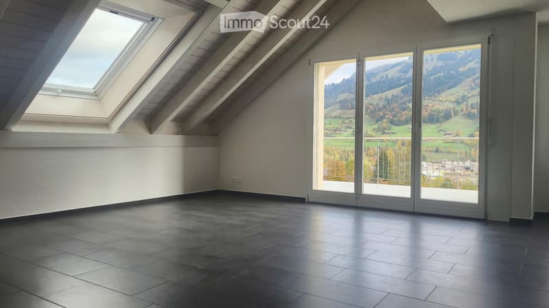 Empty attic room with skylight windows, large sliding glass doors opening to a balcony, and a view of the countryside.
