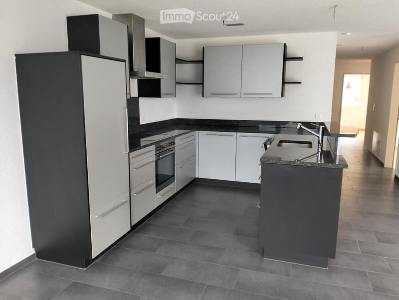 Modern kitchen with white and black cabinets, stainless steel appliances, dark countertops, and tiled flooring.
