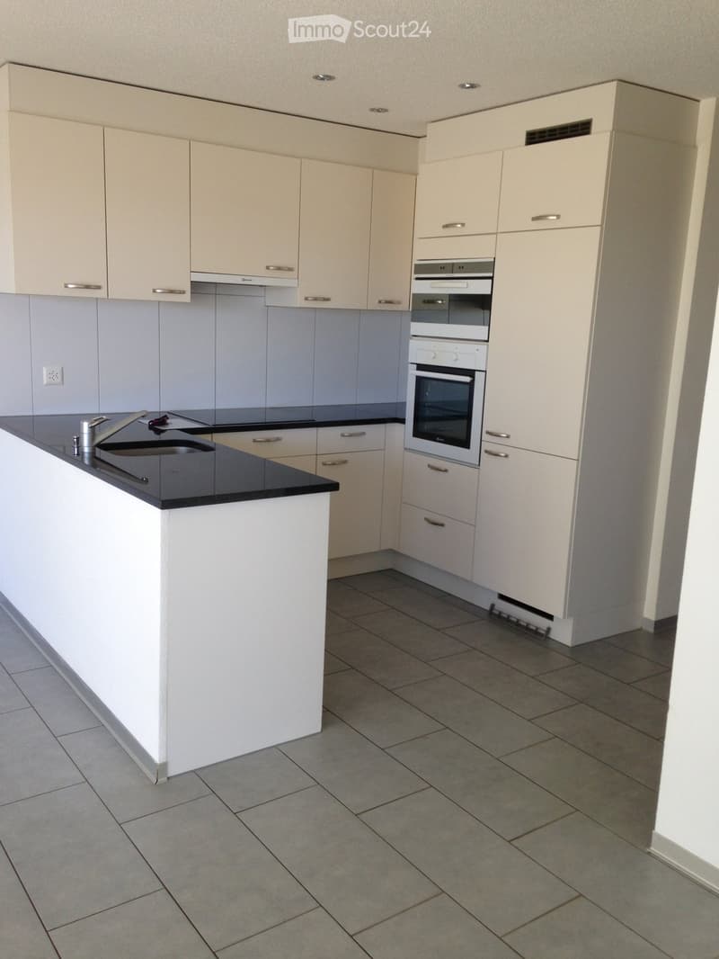 Kitchen. Modern kitchen with white cabinets, black countertop, and built-in oven. Features a central island with sink and ample storage space.
