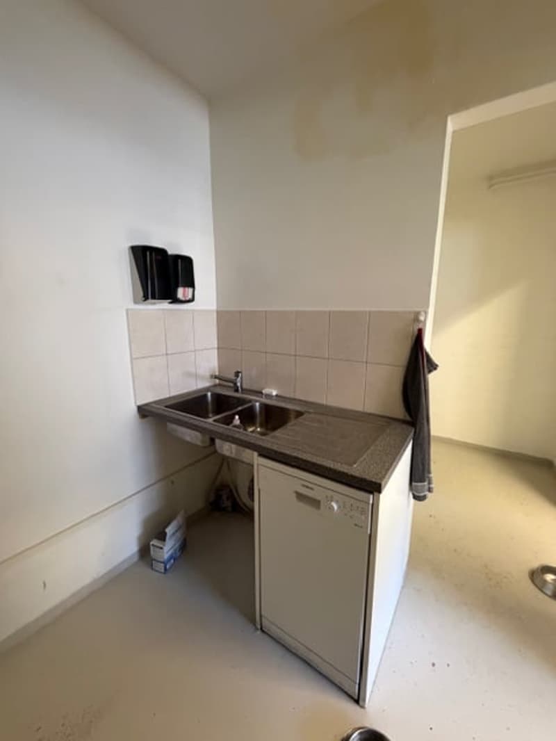 Empty kitchen with a sink, faucet, and dishwasher. Tiled walls and floor.