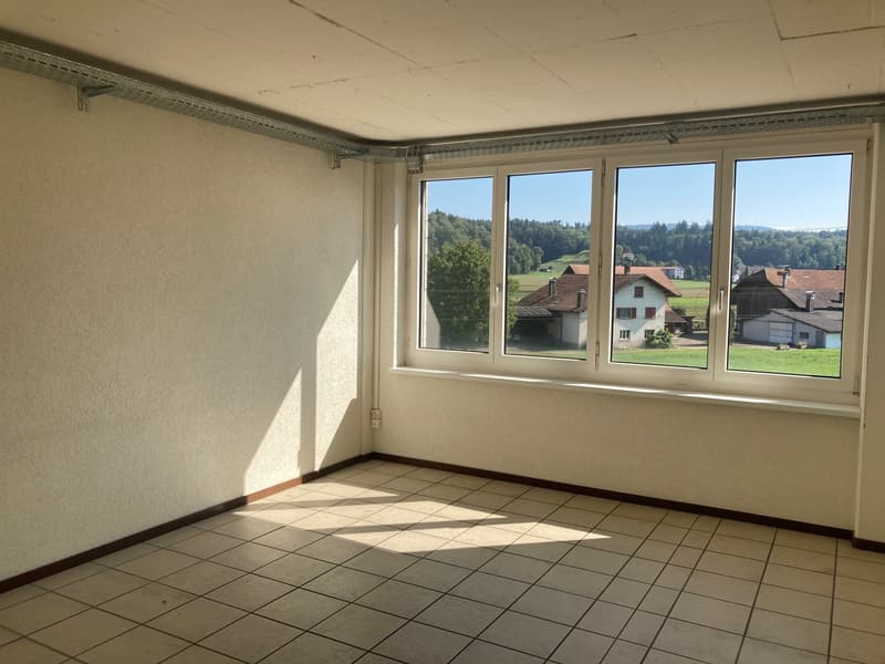 Empty room, white walls, tile floor, large window with view of houses and trees