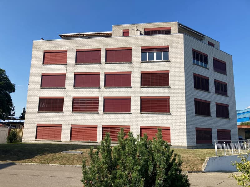 4-story white brick building with red shutters, concrete fencing, greenery