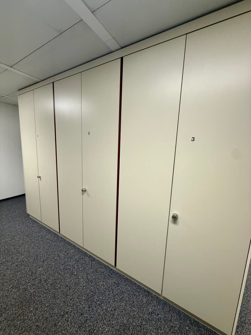 Large white cabinet units, numbered 1 to 3, empty storage room, carpeted floor, white ceiling