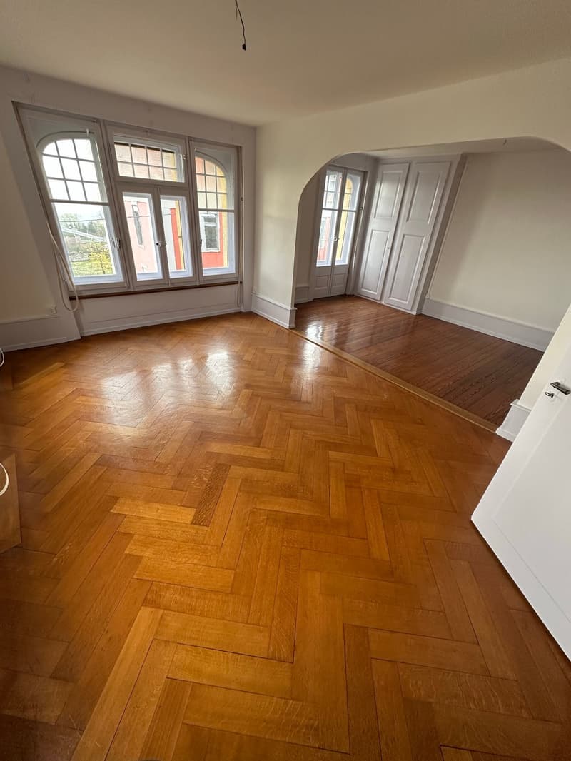 empty room, parquet floor, white walls, 3 arched doorways, large windows, wooden door