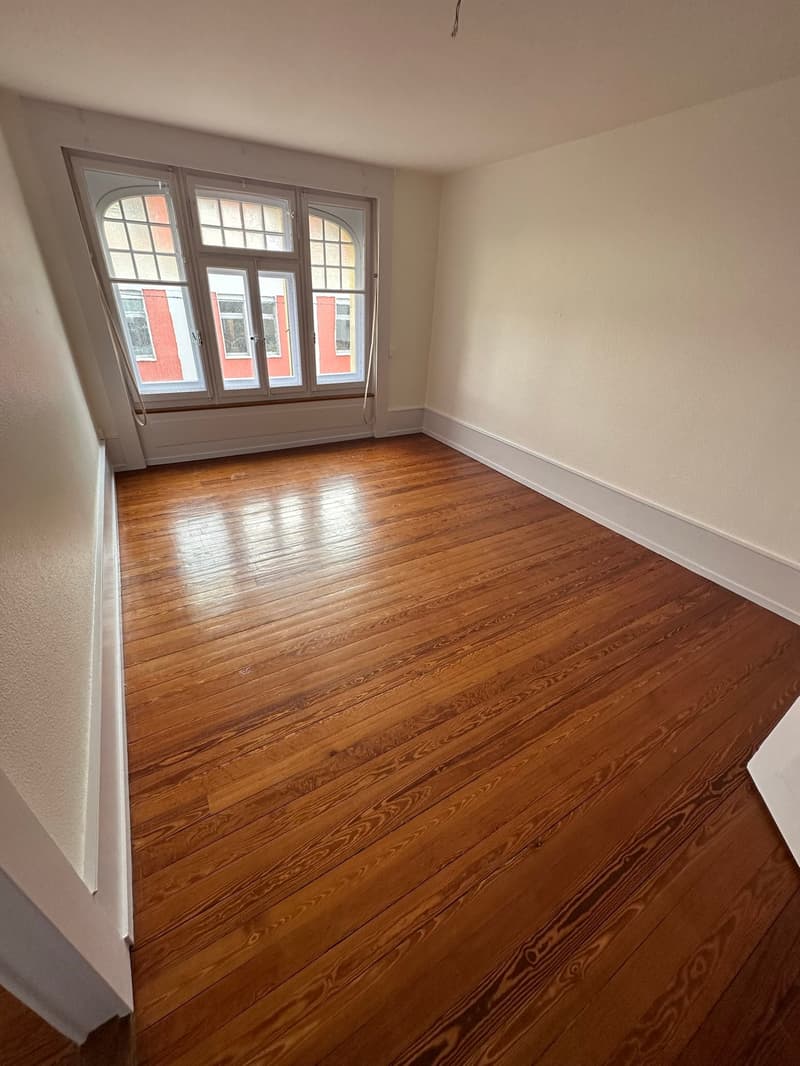 large wooden floor, white walls, large window, empty room