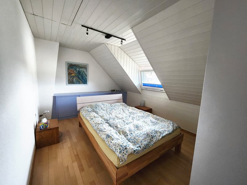 bedroom with wooden bed, wooden nightstands, wooden floor, white walls, blue headboard, picture frame, skylights, wooden ceiling