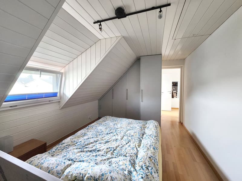 Bedroom with bed, wardrobe, window, wooden floor, white walls, ceiling lights