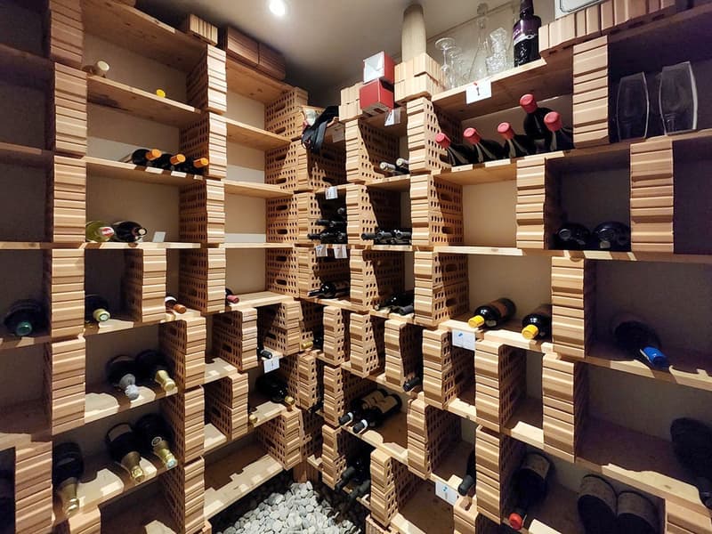 Wine cellar with wooden shelves, wine bottles, wine glasses, and other wine-related items