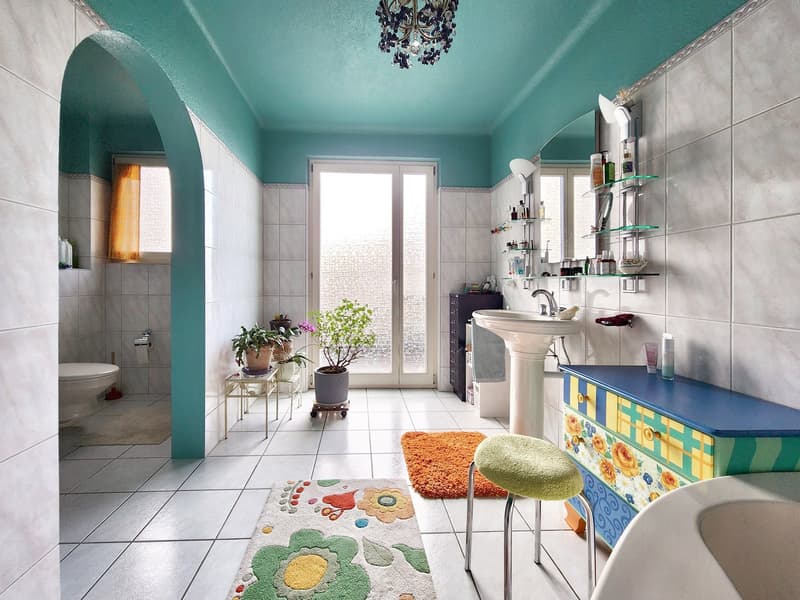 white tiles, blue ceiling, white sink, blue cabinet, rug, stool, plants, mirror, shelves