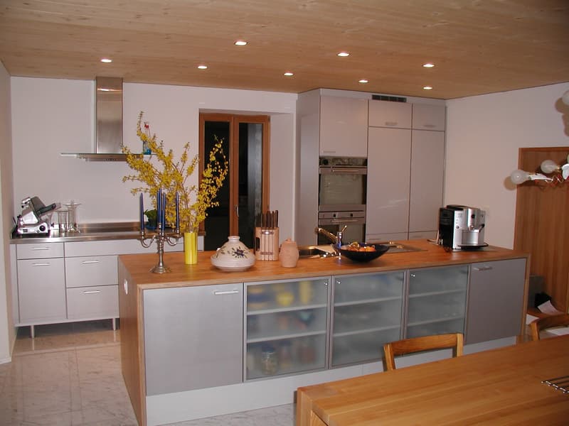 modern kitchen, wooden countertops, stainless steel appliances, white cabinets, large windows, chandelier, dining table