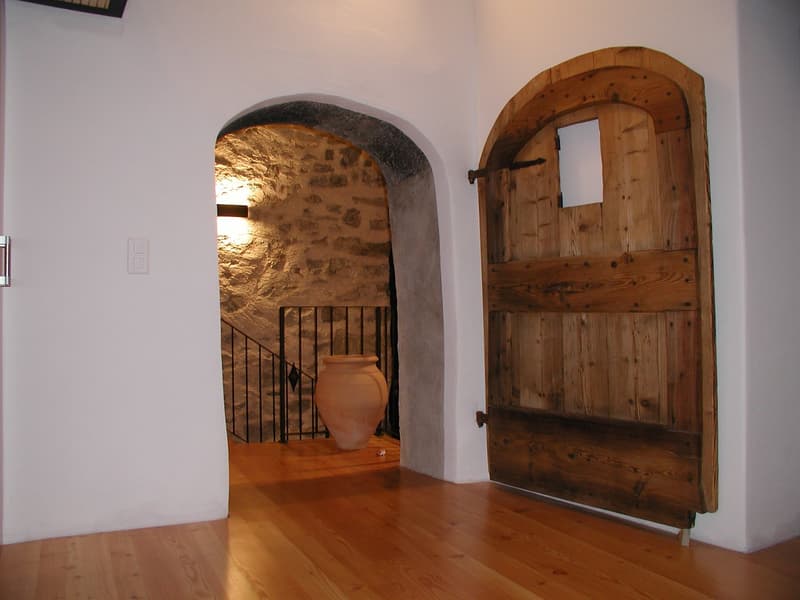 wooden door, white wall, wooden floor, stone wall, large vase, light