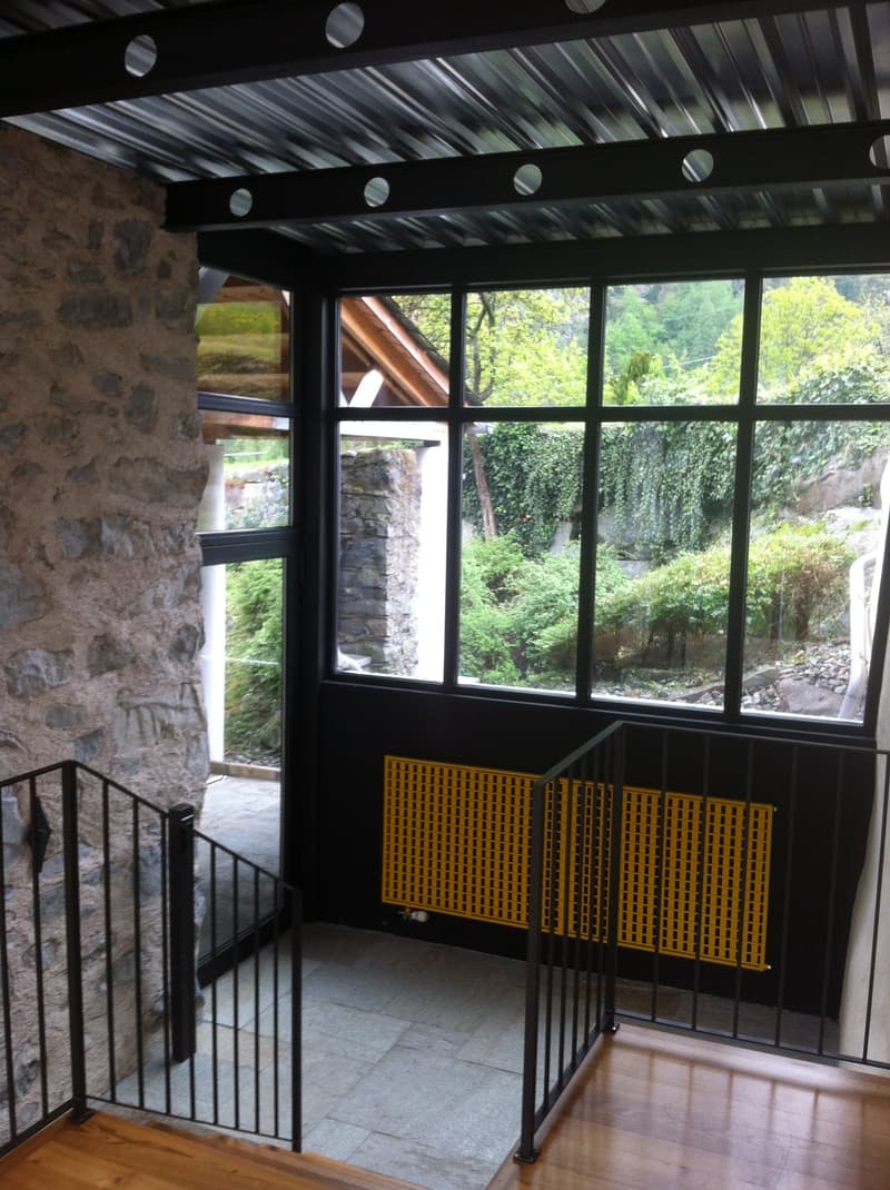 Stone wall, black railings, large windows, wooden floor, yellow radiator