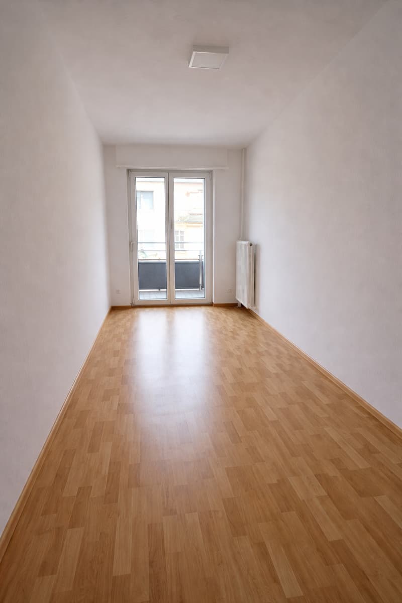 empty room, wooden floor, sliding glass door, balcony, white walls, white ceiling, white radiator