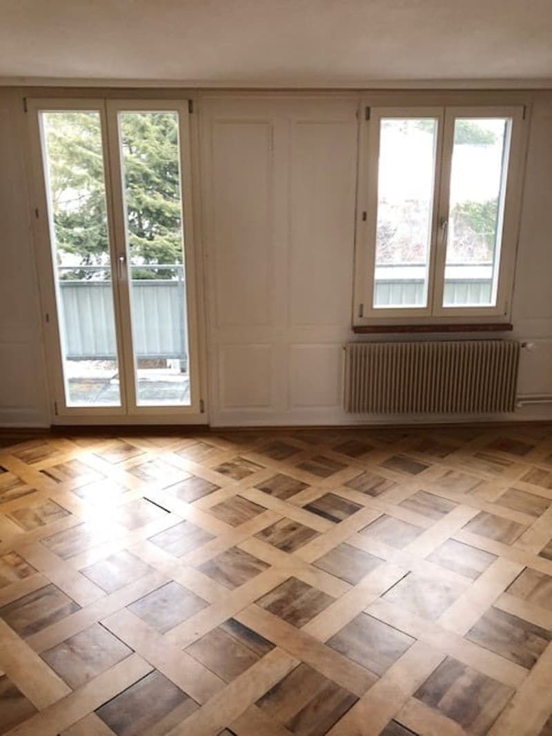 empty room, wooden parquet floor, sliding glass doors, white walls, windows, radiator