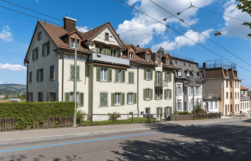 3 story building, brown roof, green shutters, balconies, street view
